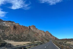 Open road through Teide National Park in Tenerife with volcanic rock and blue sky
