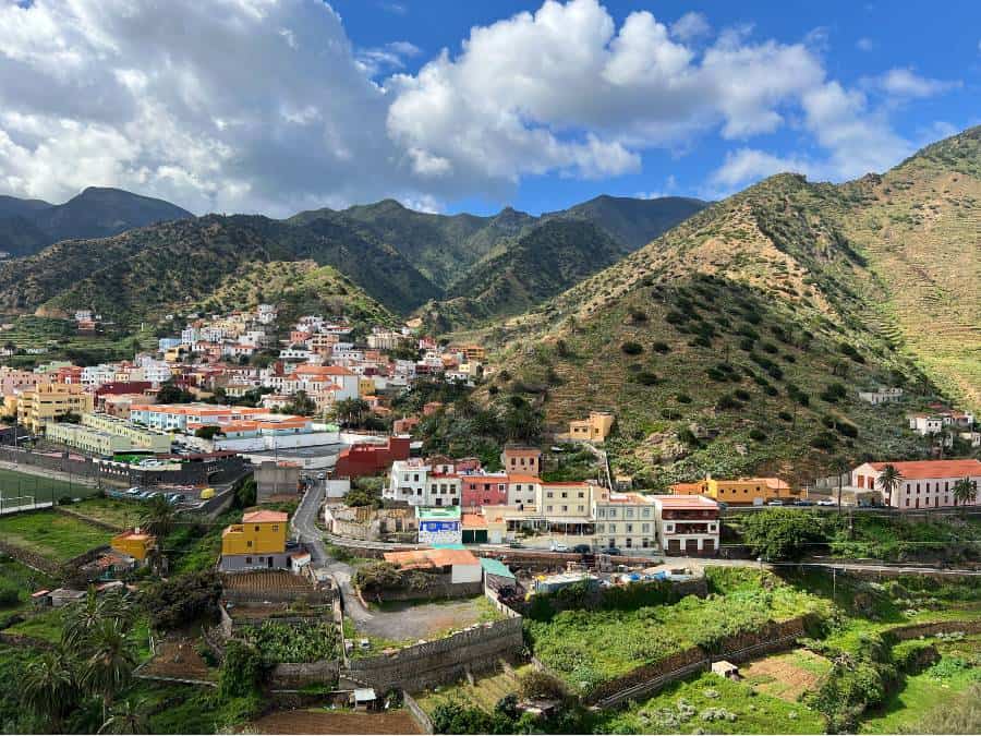 Colourful hillside town on La Gomera with green mountains behind it.