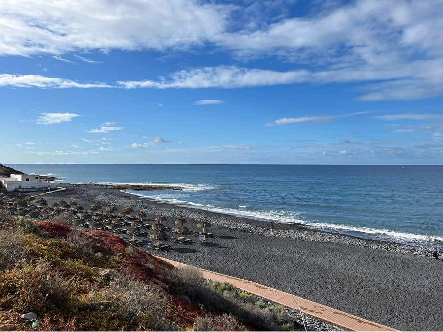 Playa de la Enramada black-sand beach in South Tenerife with the sea and promenade.