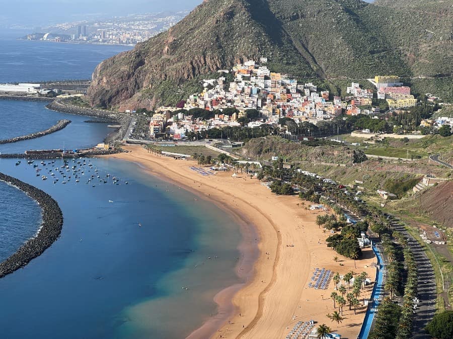 View over Playa de las Teresitas near Santa Cruz de Tenerife with golden sand, calm water, San Andrés village and mountains behind.
