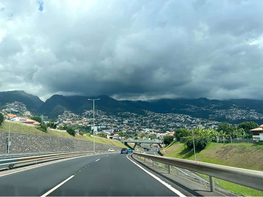 Madeira expressway VR1 heading toward Funchal with dramatic clouds over the mountains.