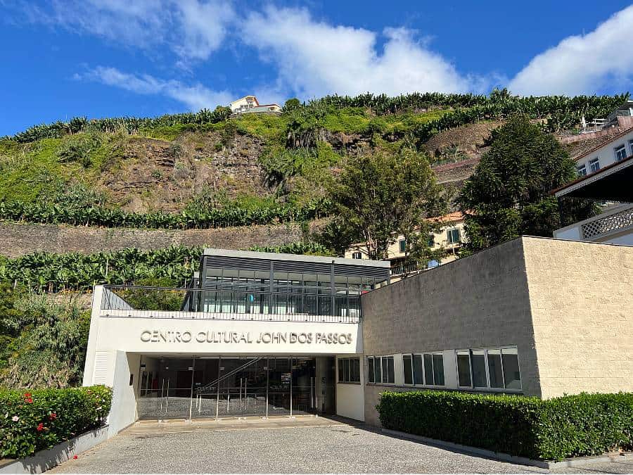 Exterior of the John dos Passos Cultural Centre with banana terraces behind