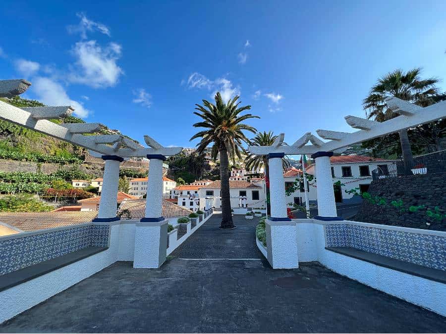 Miradouro Infante Dom Henrique viewpoint with palm trees, white pergolas, and mountain terraces in Ponta do Sol, Madeira