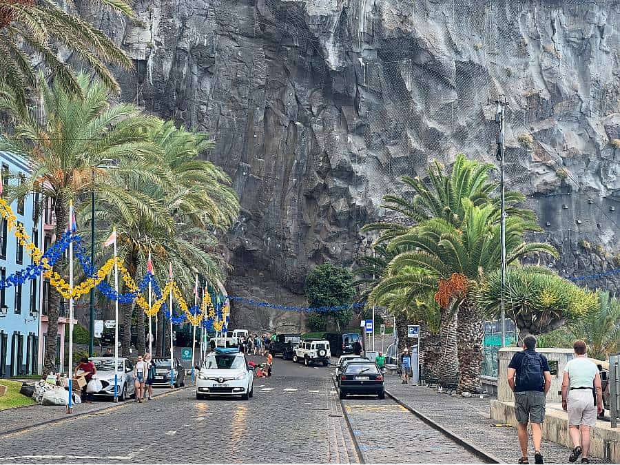 Palm-lined promenade and colourful buildings in Ponta do Sol, Madeira, with dramatic cliff backdrop.
