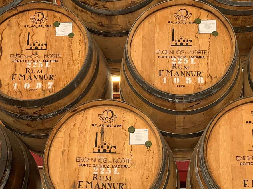 Close-up of rum barrels stacked at Engenhos do Norte distillery, each labelled with Porto da Cruz and Madeira branding