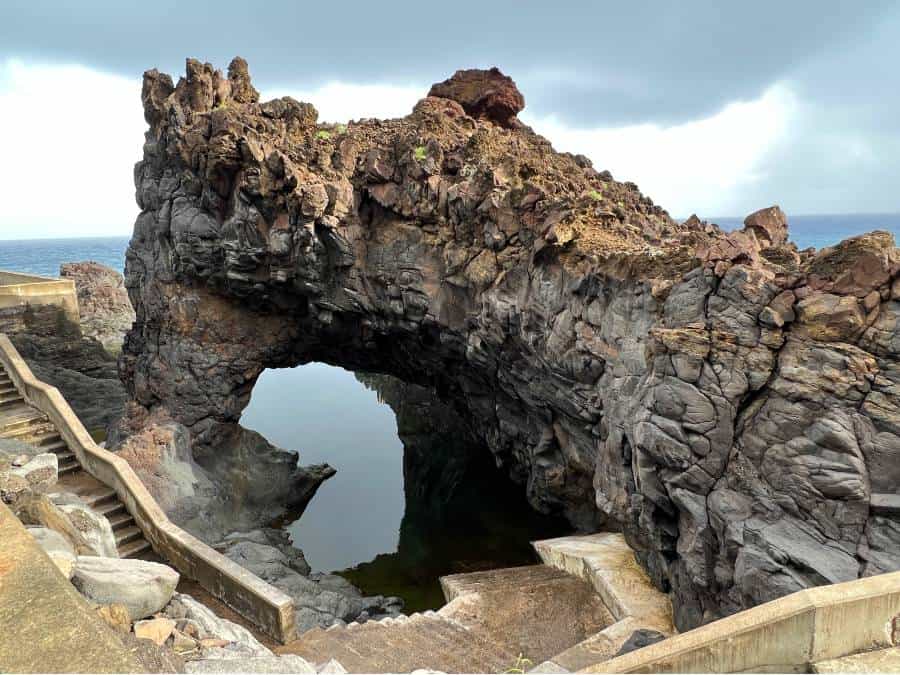 gIANT ARCH IN ROCK WITH WATER AND STEPS DOWN