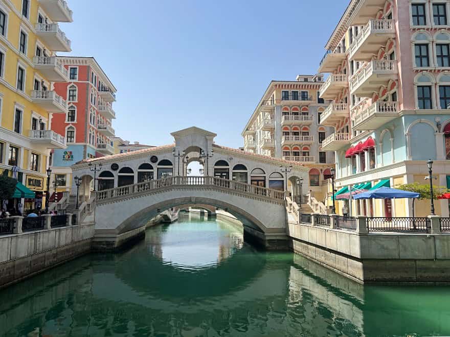 colourful buildings either side of a canal with a small bridge over it.