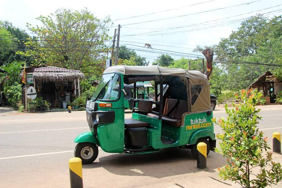 a green tuktuk on a street in Sri Lanka