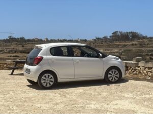 Compact white rental car parked at a scenic viewpoint — perfect example of checking parking and vehicle condition before hitting the road.