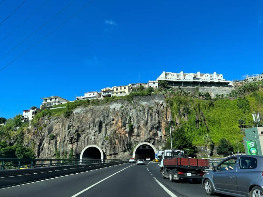 Driving through a tunnel on Madeira’s main road with cliffs and hillside houses above