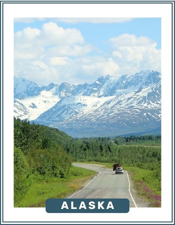 Image of a long road in Alaska, with snow-capped mountains in the foreground and green forest either side.