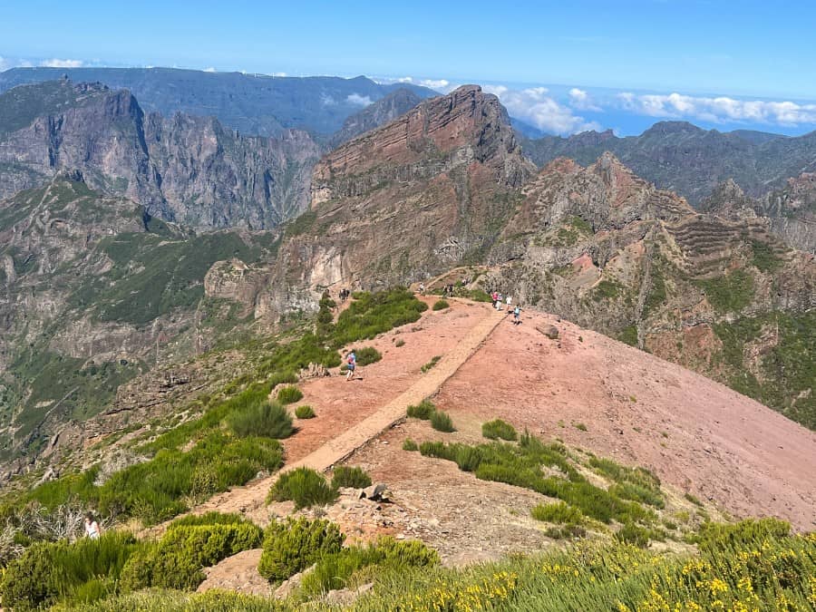Mountain ridge viewpoint on a Madeira hike with hikers and dramatic peaks in the background.