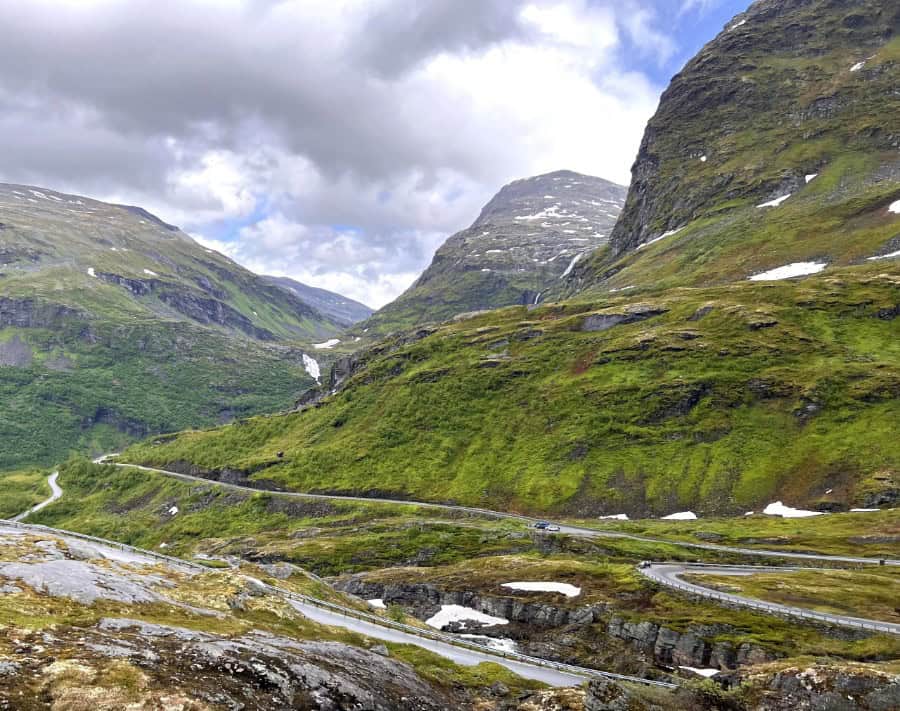 Winding Norwegian Road beside steep mountains showing why driving days can take longer